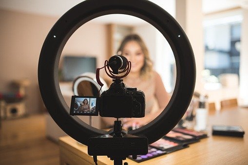 A young woman vlogging herself doing makeup